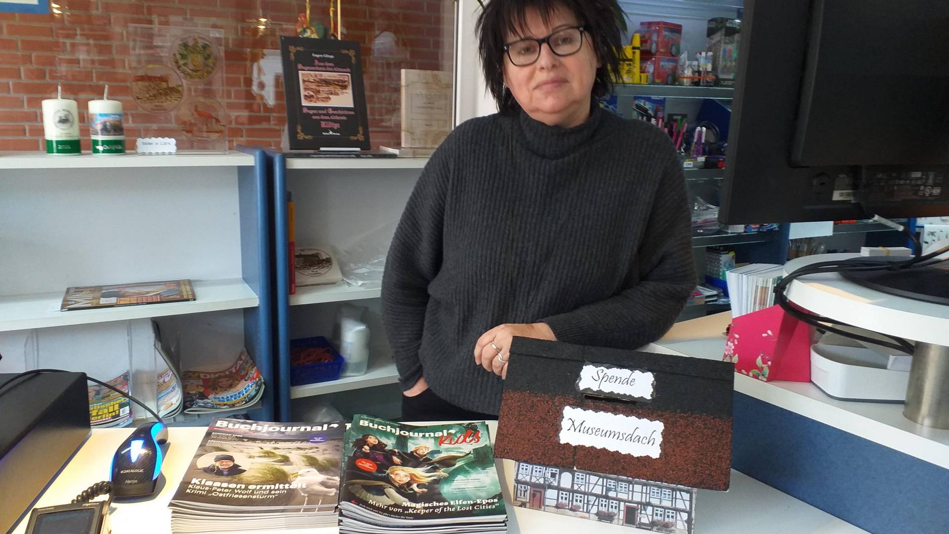 Marlies Hoffmann in ihrer Buchhandlung mit einem Spendenhäuschen, das dem Museum nachempfunden ist. © Heimatverein Oebisfelde